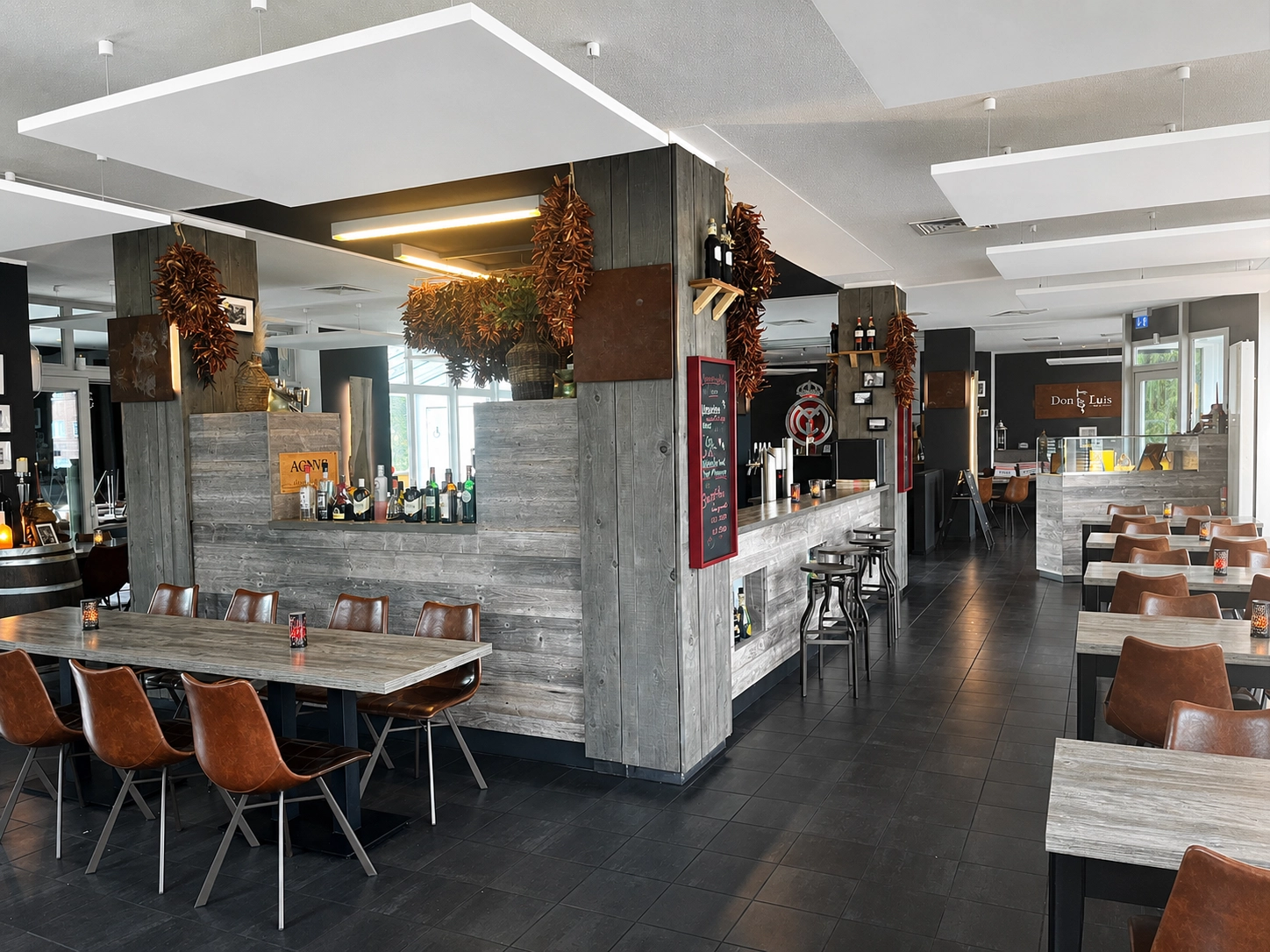 Restaurant mit braunen Lederstühlen, Holztischen und Bartheke.